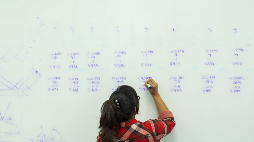 A University of Tennessee graduate student writing calculations on dry erase board