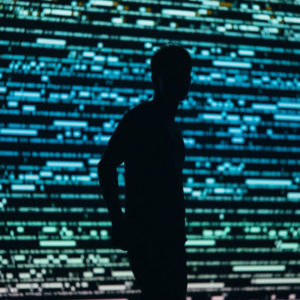 Silhouette of a man photographed in front of a large digital monitor, image by Chris Yang.